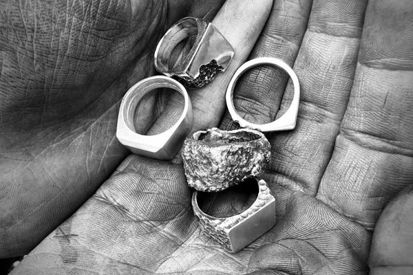 Händer som håller i fem ringar i silver från en silversmideskurs hos Hjertsmide