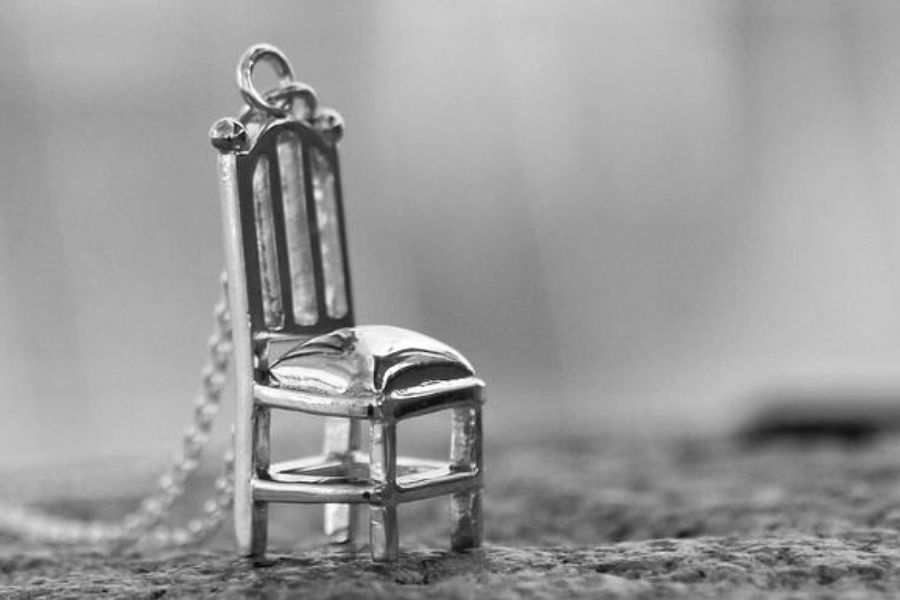 Närbild på ett personligt och unikt silverhalsband med formen som en stol